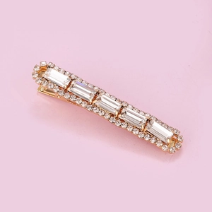 Macro shot of rectangular gold hair clip with large clear crystals and small rhinestones