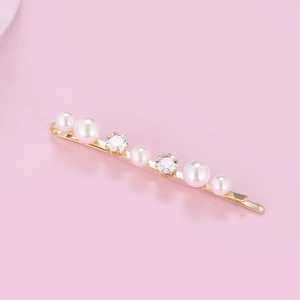Close-up of golden hair clip featuring alternating gradient pearls and shining rhinestones