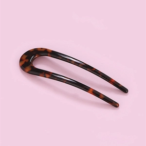 Macro detail of the U-shaped hair pin featuring classic amber tortoiseshell texture
