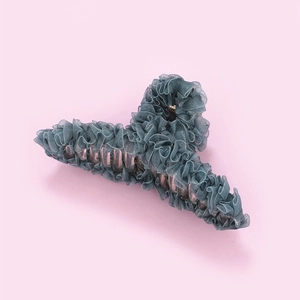 Pince à cheveux élégante en dentelle vert sauge avec détails à volants sur fond rose uni