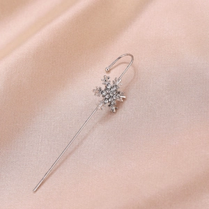 Detail of silver snowflake ear cuff with sparkling zircon inlay on champagne silk background