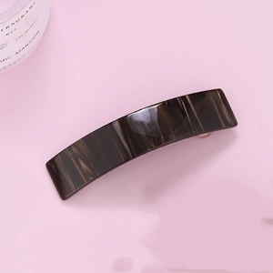 Detail of a dark marble pattern hair claw clip with a glossy finish on a pink background