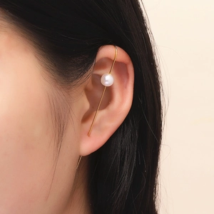 Detail view of a pearl gold crawler earring on a model's ear with lightning bolt design