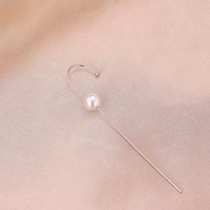 Close-up of minimalist silver ear cuff with single pearl on champagne satin background