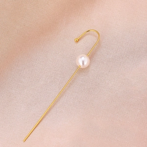 Detail of minimalist gold pearl hook earring on soft pink silk background