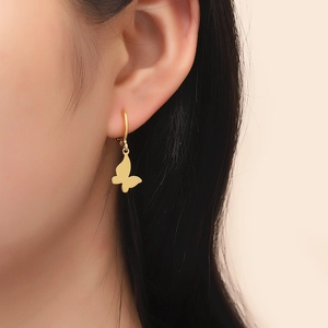 Close-up of minimalist gold butterfly hoop earring worn by a model with metal finish