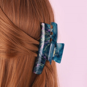 Détail de la grande pince à cheveux en acétate marbré sur de longs cheveux