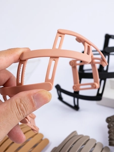Detail showing the peach-pink bird nest retractable hair clip with a matte resin finish