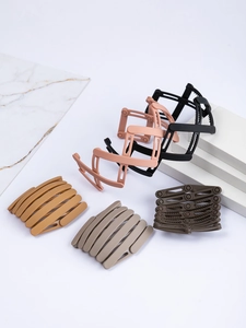 Collapsible bird nest hair clips in matte black, pink, yellow, and grey on marble tiles