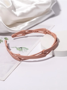 Detail of matte pink folding headband with non-slip teeth on a white satin background