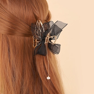 Detail of mesh bow hair claw clip with golden chain and pearl pendant on brown hair