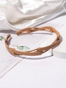 Detail view of foldable matte light brown headband with non-slip teeth and hinge structure