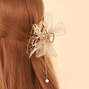 Detail of elegant gold butterfly hair claw with champagne organza bow and pearl tassel