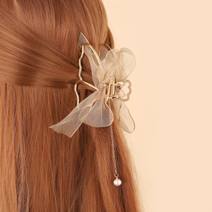 Detail of elegant gold mesh bow hair claw with pearl tassel on long brown hair