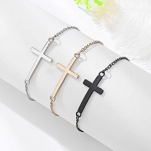 Ensemble de trois bracelets croix en argent, or et noir sur un support de présentation