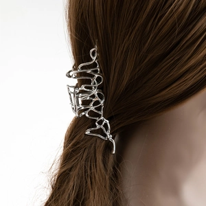 Détail de la pince à cheveux en métal liquide argenté au design creux irrégulier
