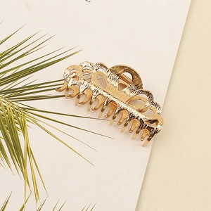 Macro shot of gold metal hair claw with hollow floral design and textured finish