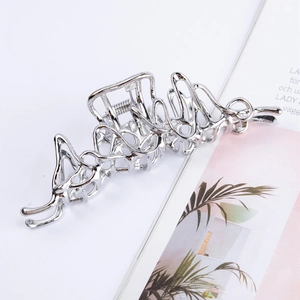 Détail de la pince à cheveux en métal argenté liquide au design irrégulier et brillant