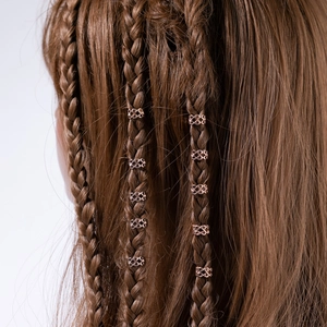 Détail de bagues de cheveux en spirale creuse or rose sur des tresses brunes