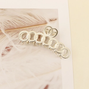 Detailed close-up of matte silver alloy hair claw with intricate spiral ring texture