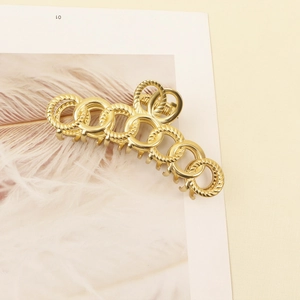 Elegant gold geometric metal hair claw clip with twisted rings on a display card