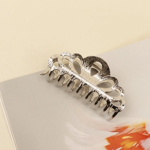 Close-up of vintage hollow floral silver metal hair claw clip on a white magazine