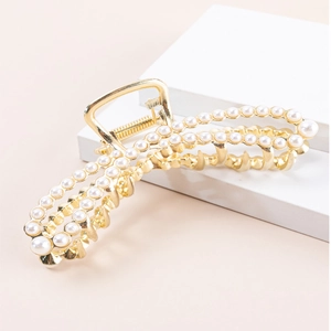 Detail of a gold metal hair claw clip featuring two rows of elegant white pearls
