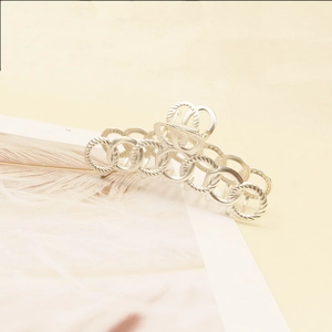 Macro detail of a large matte silver hair claw with a unique chain ring design