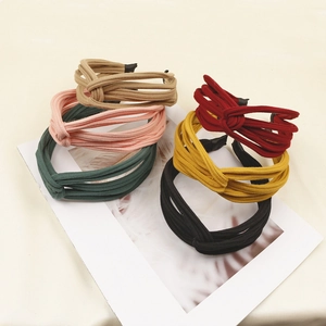 Detail showing various colors of knitted knot headbands with striped texture fabric