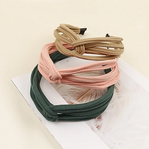 Close-up of three knotted ribbed fabric headbands in khaki, pink, and dark green colors