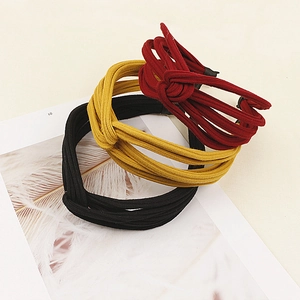 Close-up of three knitted knotted headbands in black, ginger yellow, and wine red colors