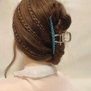 Eleganter silberner Haarklammer mit blauen Steinen am Hinterkopf eines Models getragen