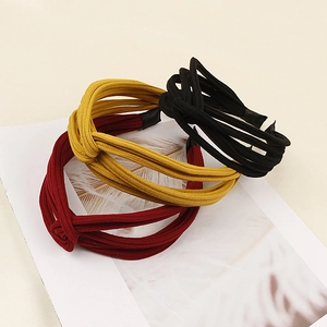 Close-up of three knitted knotted headbands in burgundy, ginger, and black colors