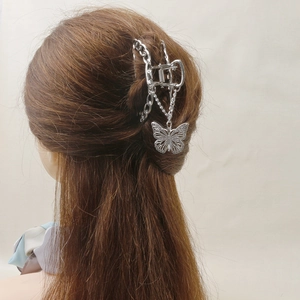 Détail d'une pince à cheveux papillon argentée avec pampilles à franges métalliques