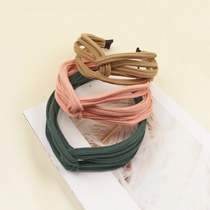 Three stylish knitted twist headbands in brown, orange, and green on a magazine background