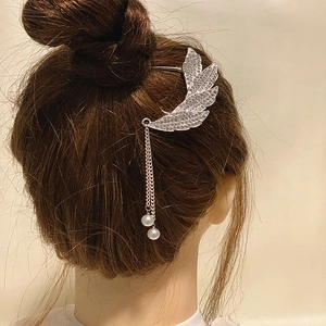 Détail de la pince à cheveux aile argentée avec strass et élégants pompons en perles