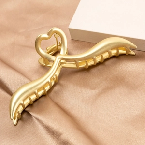 Pinza para el pelo elegante de metal dorado con forma de corazón sobre seda champán