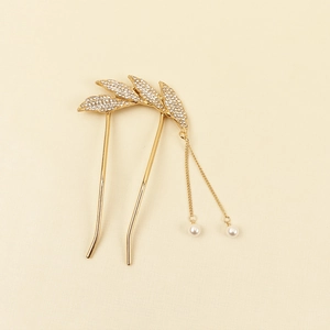 Détail de l'épingle à cheveux en or avec strass brillants et pompons en perles