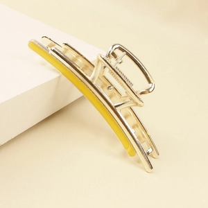 Detailed macro view of yellow enamel inlay on a golden minimalist metal hair claw clip