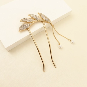 Détail d'une épingle à cheveux dorée en U avec feuilles en strass et pompons de perles