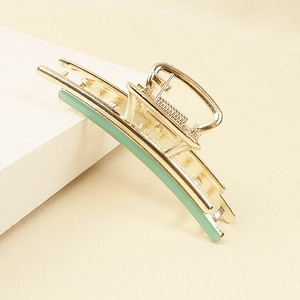 Detail view of a gold-tone alloy hair claw clip with light green enamel strip inlay