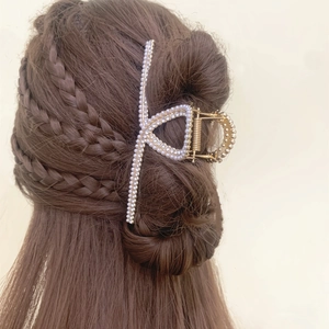 Elegante gouden metalen haarklem met parels en strass op bruin haar geplaatst