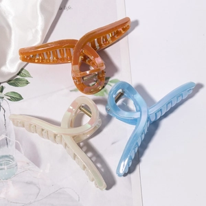Three large iridescent pearl hair claws in amber, blue and white on silk background