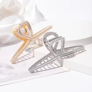 Elegante gouden en zilveren haarklemmen met parels op een geometrische standaard