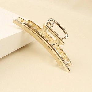 Detail of a minimalist gold alloy hair claw clip featuring polished metal finish