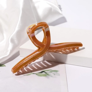 Detailed close-up of a large amber pearlescent hair claw clip on white silk display