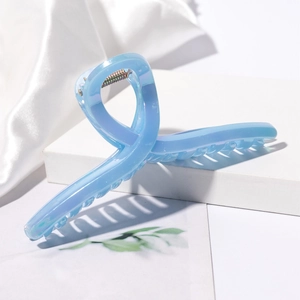 Detail of light blue iridescent hair claw clip with golden metal spring on white silk