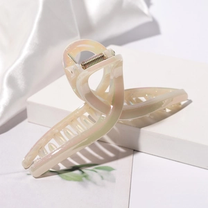 Macro detail of large iridescent hair claw clip with pearl-like finish and metal spring