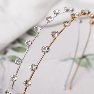 Eleganti cerchietti in metallo oro e argento con strass scintillanti su panno bianco