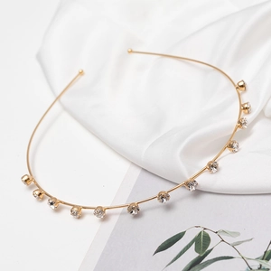 Elegant gold metal headband with sparkling rhinestones on a white silk background